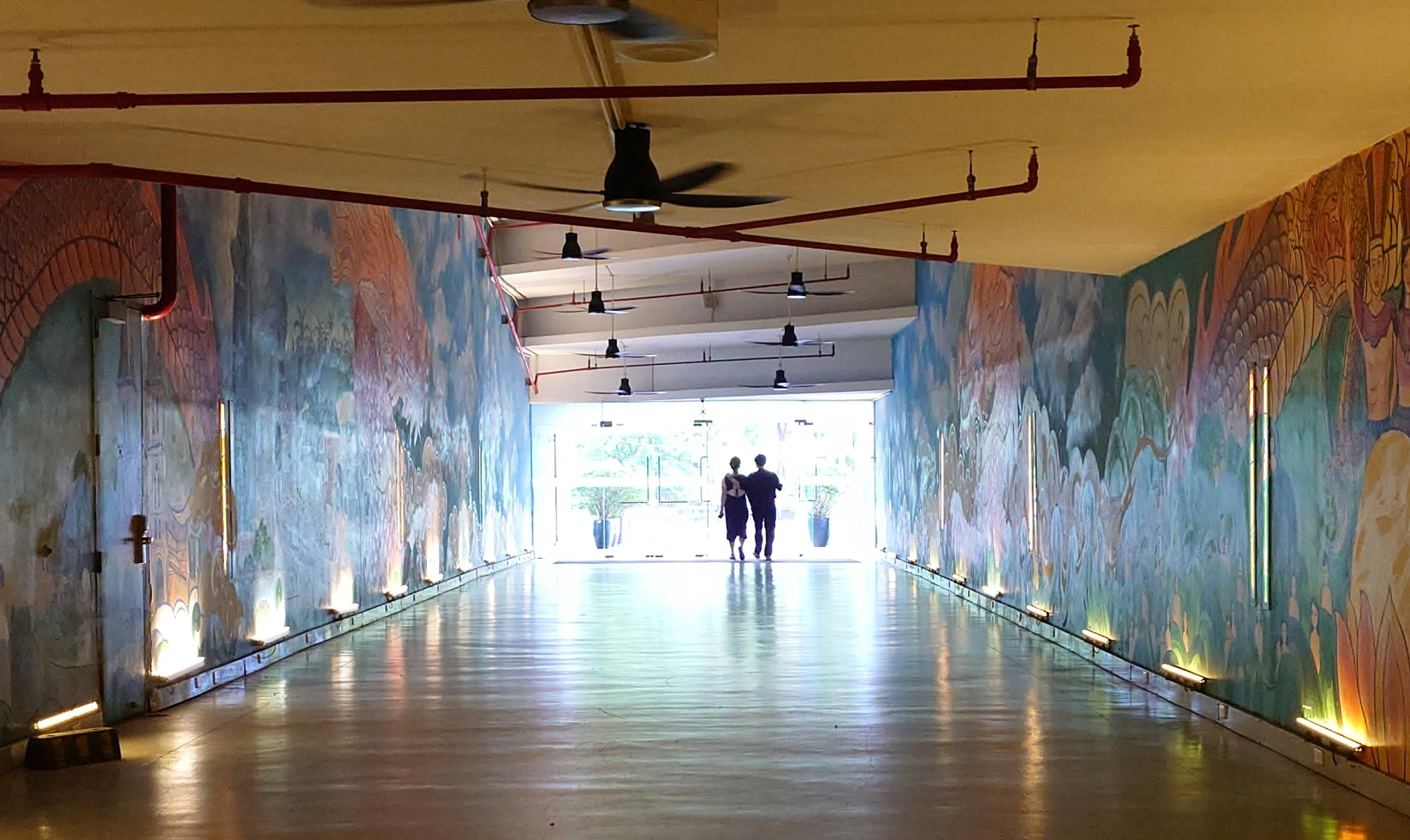 a couple of people walking down a long hallway