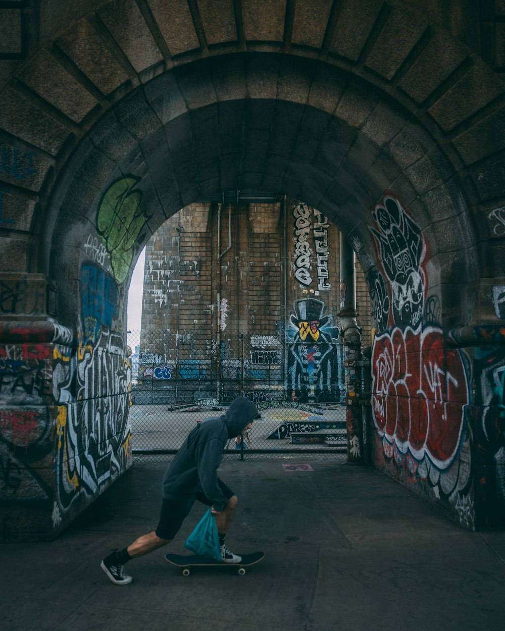 a man riding a skateboard through a tunnel covered in graffiti