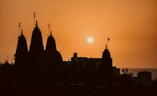 the sun is setting behind a building with spires