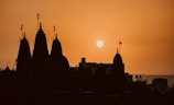 the sun is setting behind a building with spires
