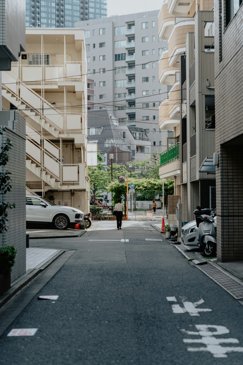 a person walking down a street next to tall buildings