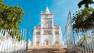 a white church with a steeple surrounded by trees
