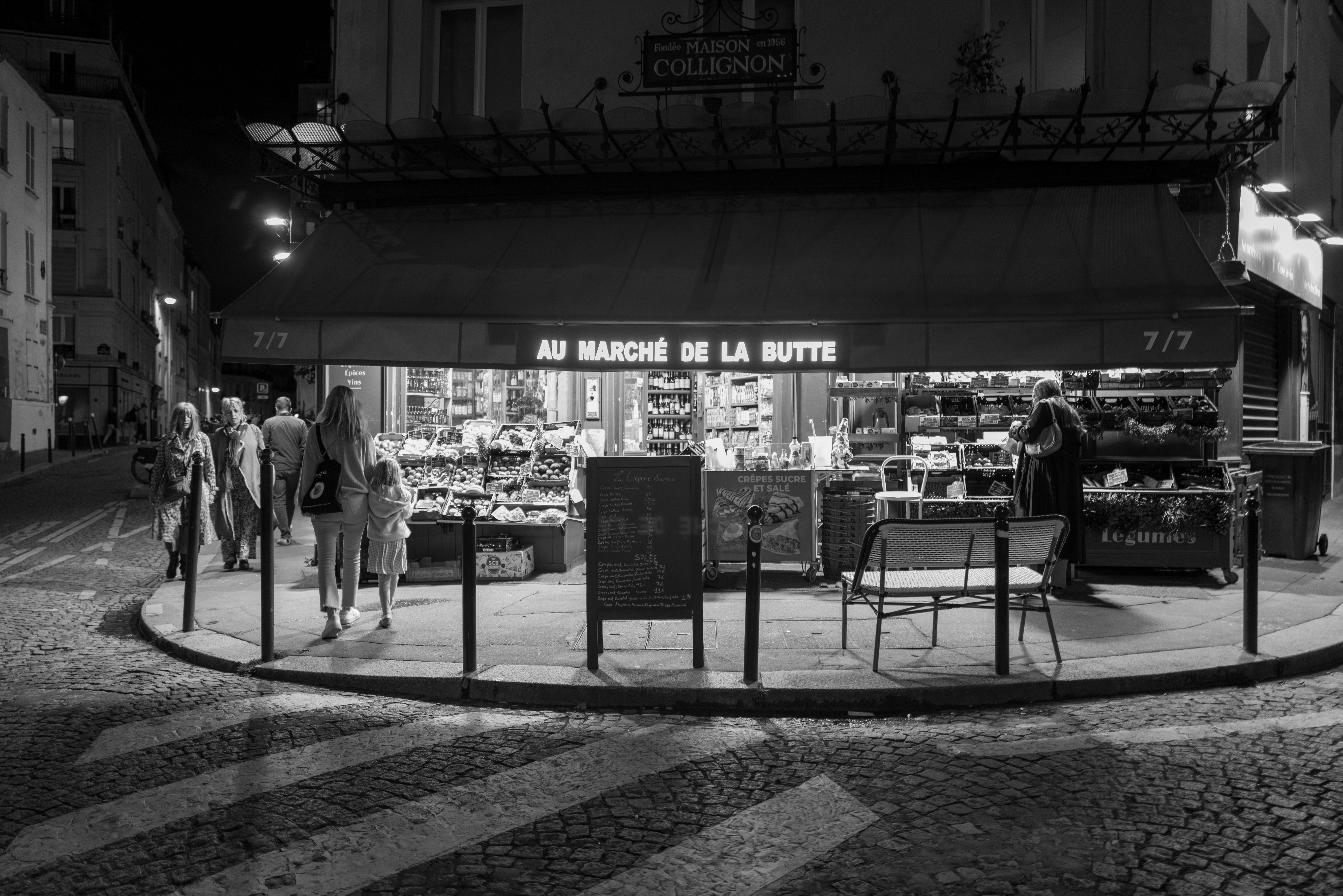 a black and white photo of people walking in front of a store