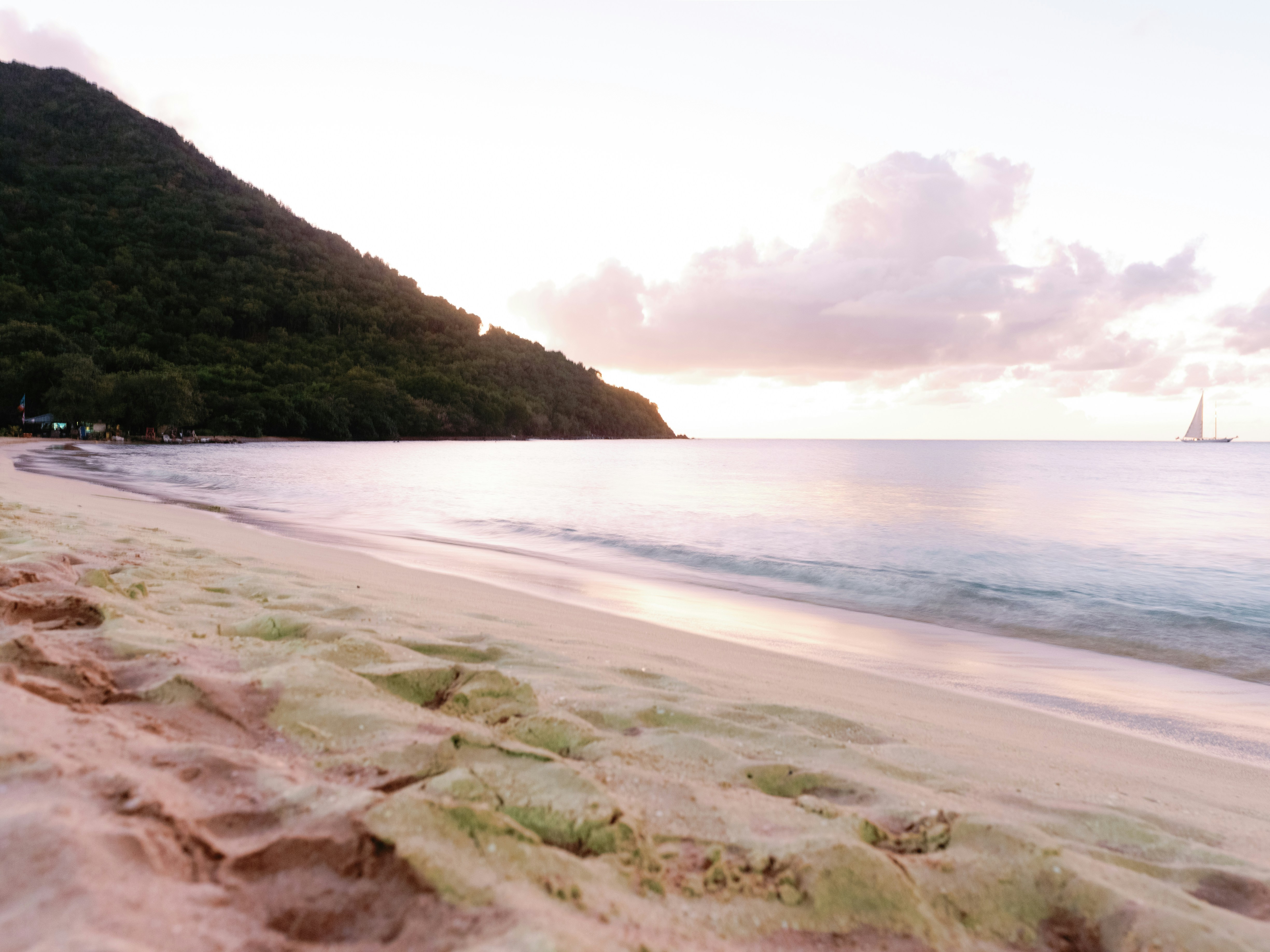 a sandy beach with a sailboat in the distance