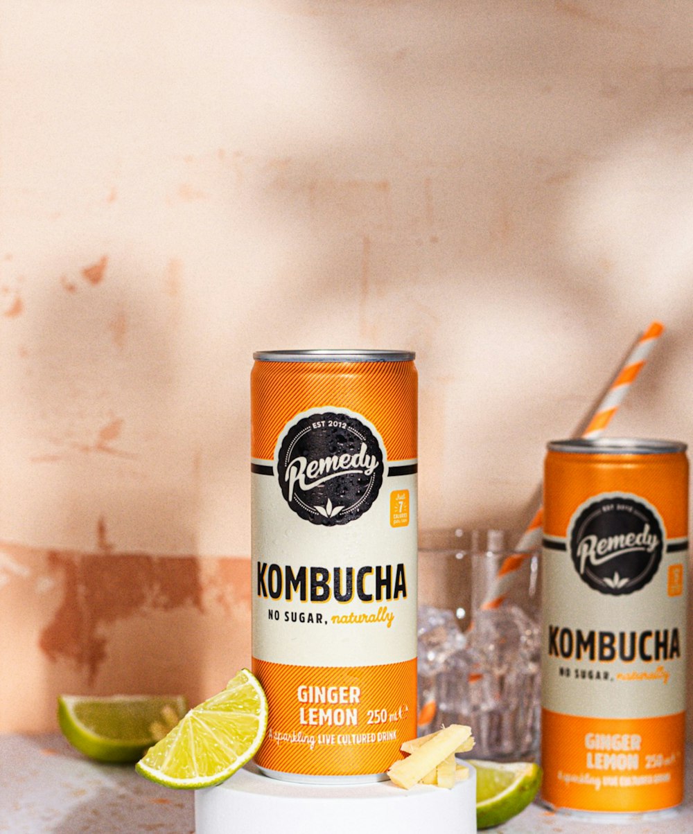a can of kombucha next to a can of ginger lemonade