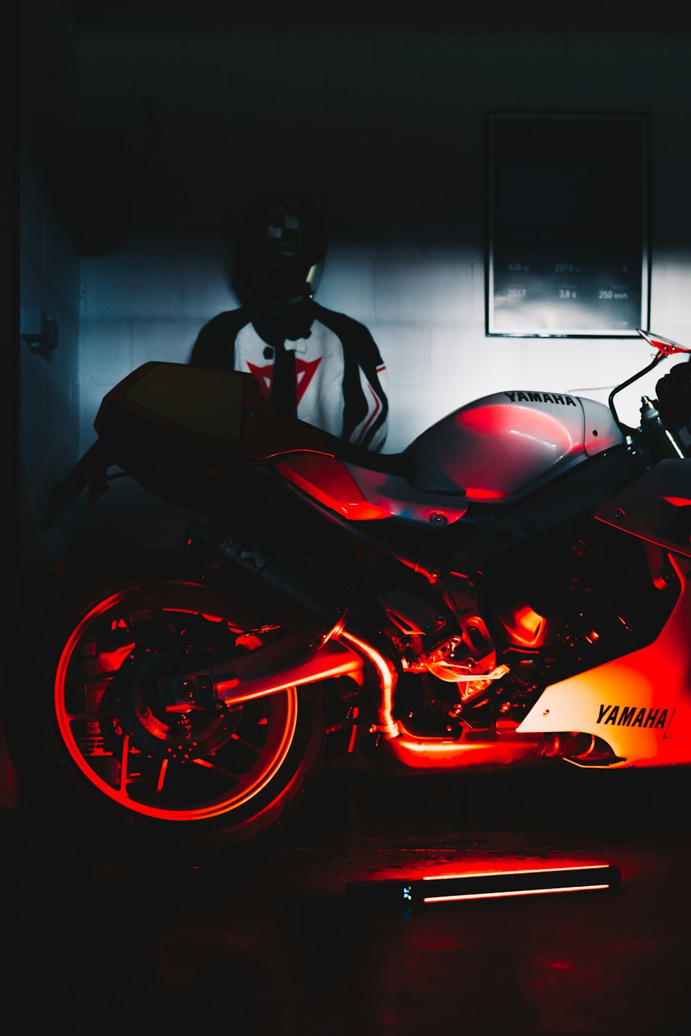 a red motorcycle parked in a garage next to a man