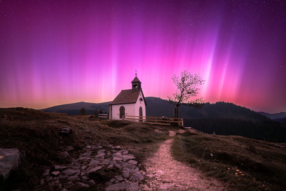 Una iglesia en una colina con las luces de la aurora al fondo