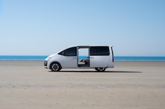 a white van parked on top of a sandy beach