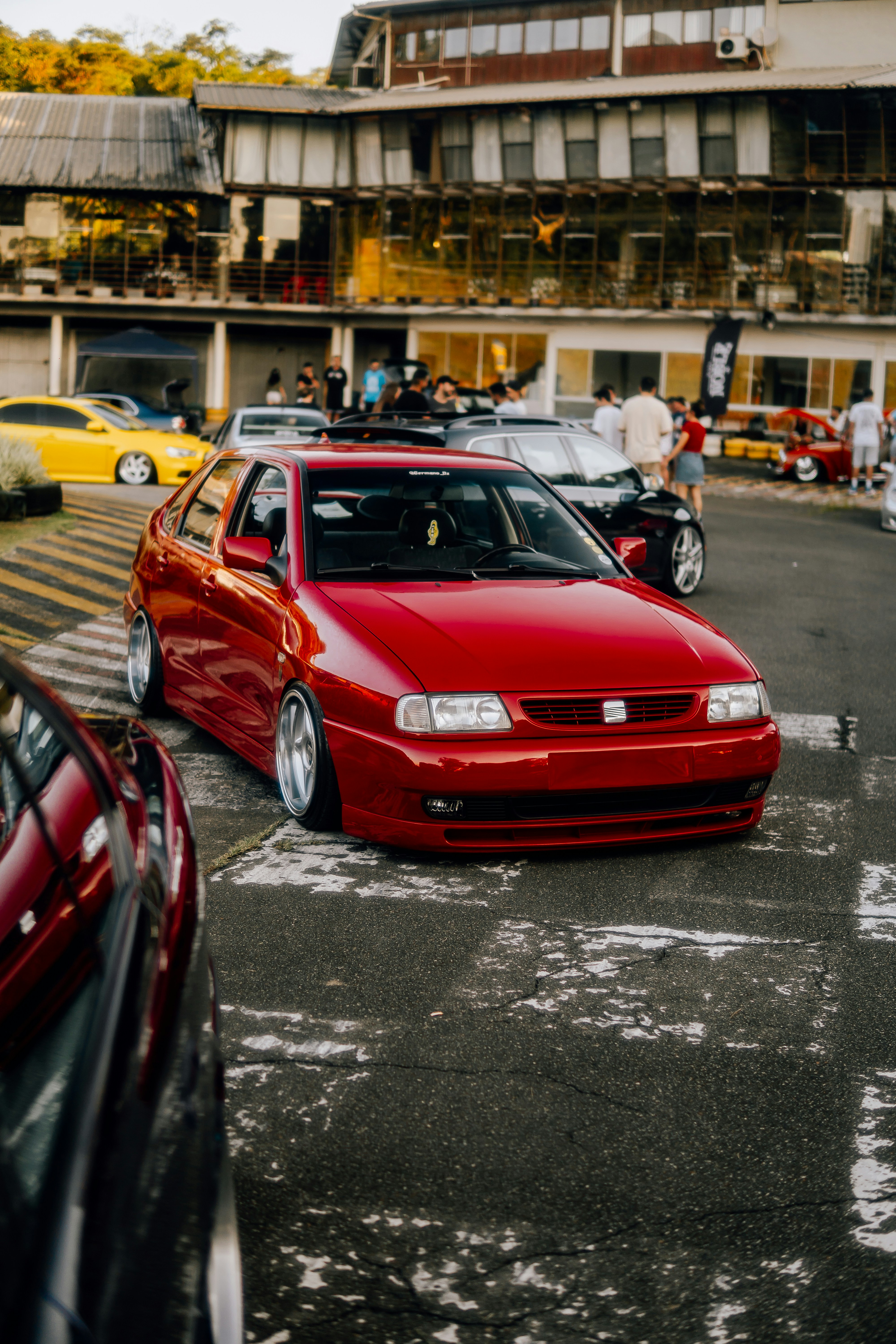 Un coche rojo aparcado en un aparcamiento junto a otros coches