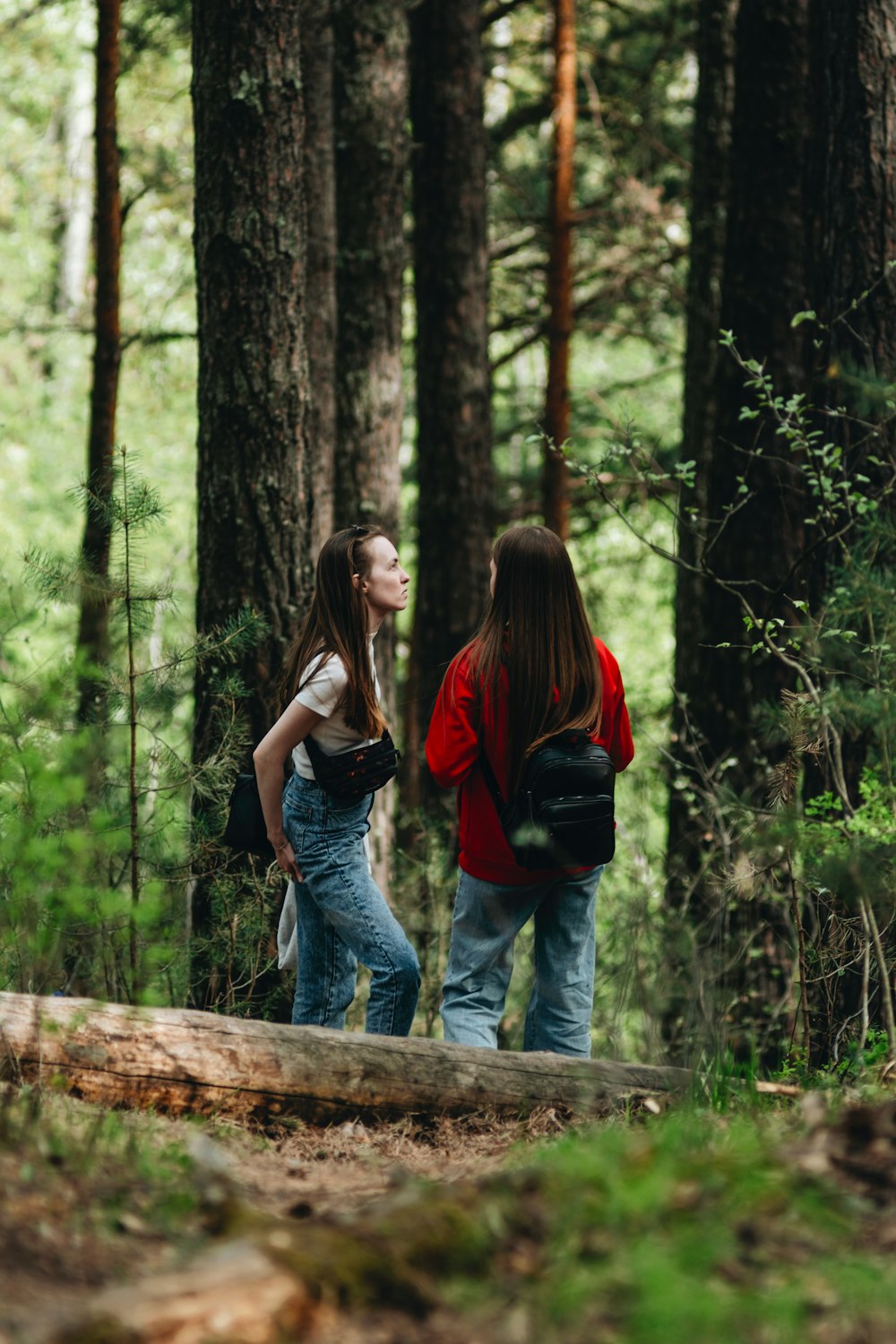 two girls walking in the woods with backpacks