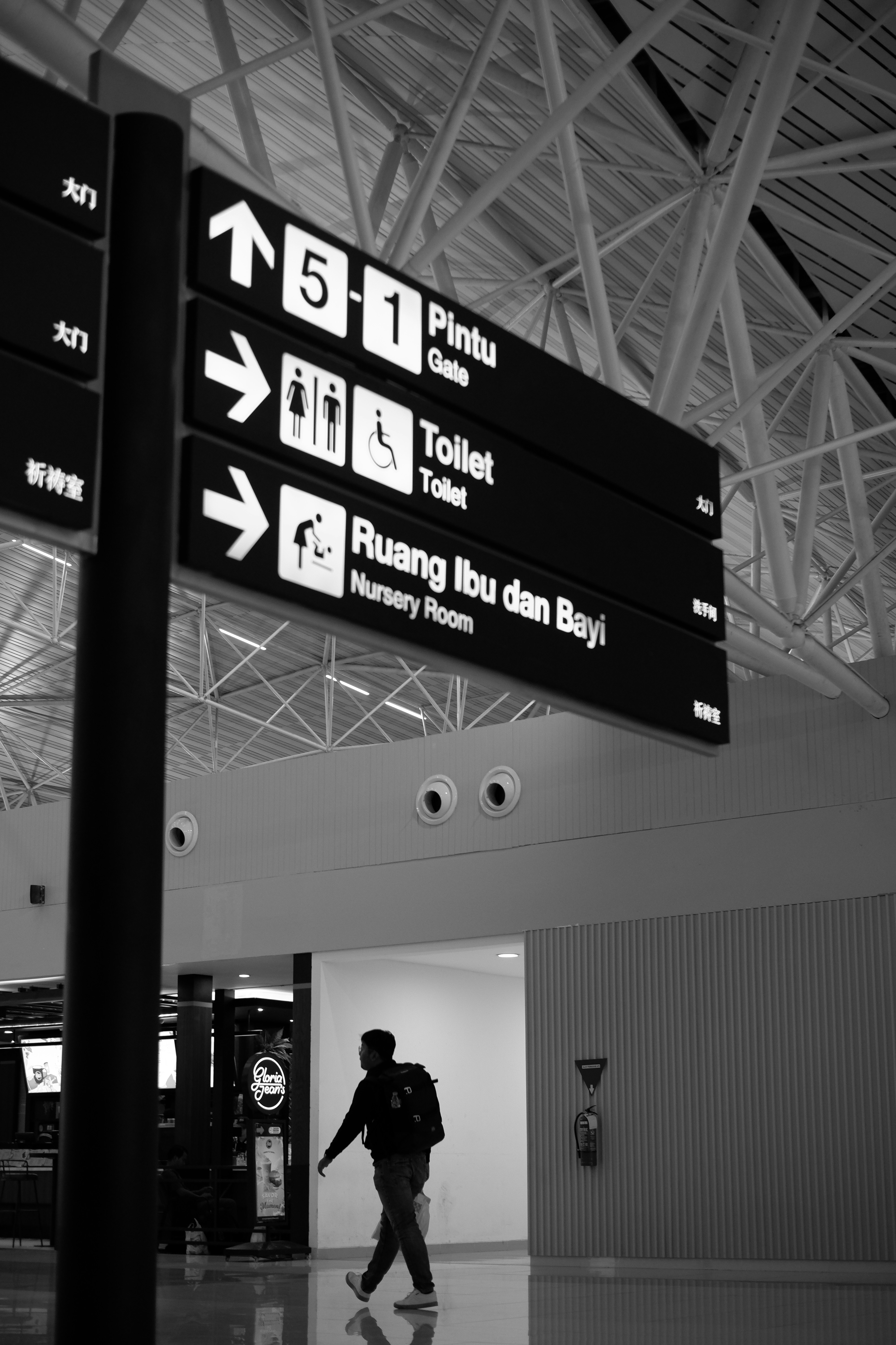 a black and white photo of a man walking through an airport