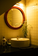 a bathroom sink with a round mirror above it