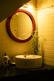 a bathroom sink with a round mirror above it