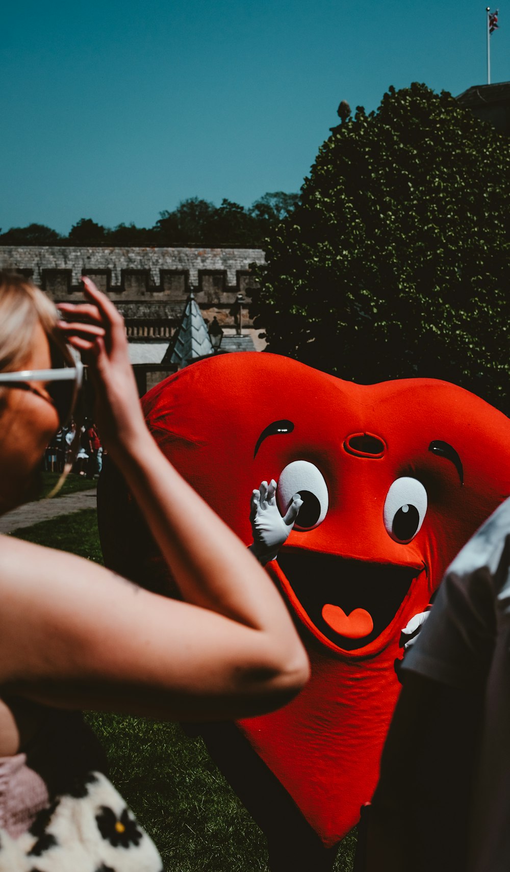 a woman taking a picture of a giant heart balloon