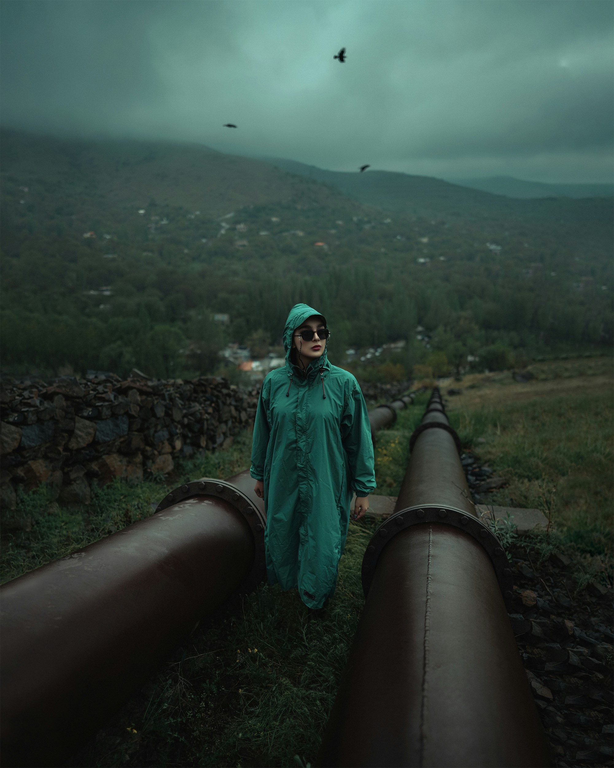 a man in a green rain suit standing next to a large pipe