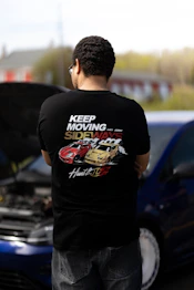 a man standing next to a car with a hood open - abbigliamento Maratona Racing