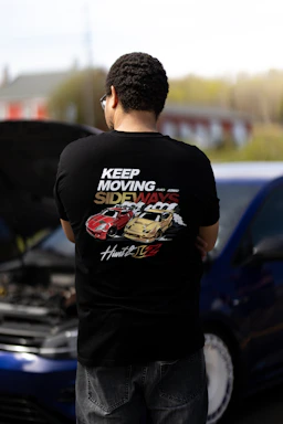 a man standing next to a car with a hood open - abbigliamento Maratona Racing