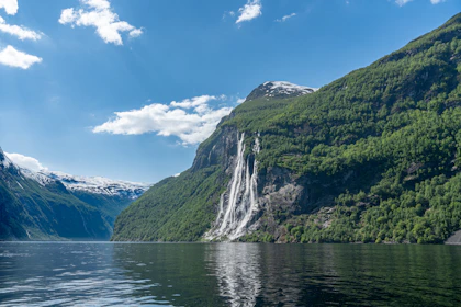 a waterfall in the middle of a lake surrounded by mountains