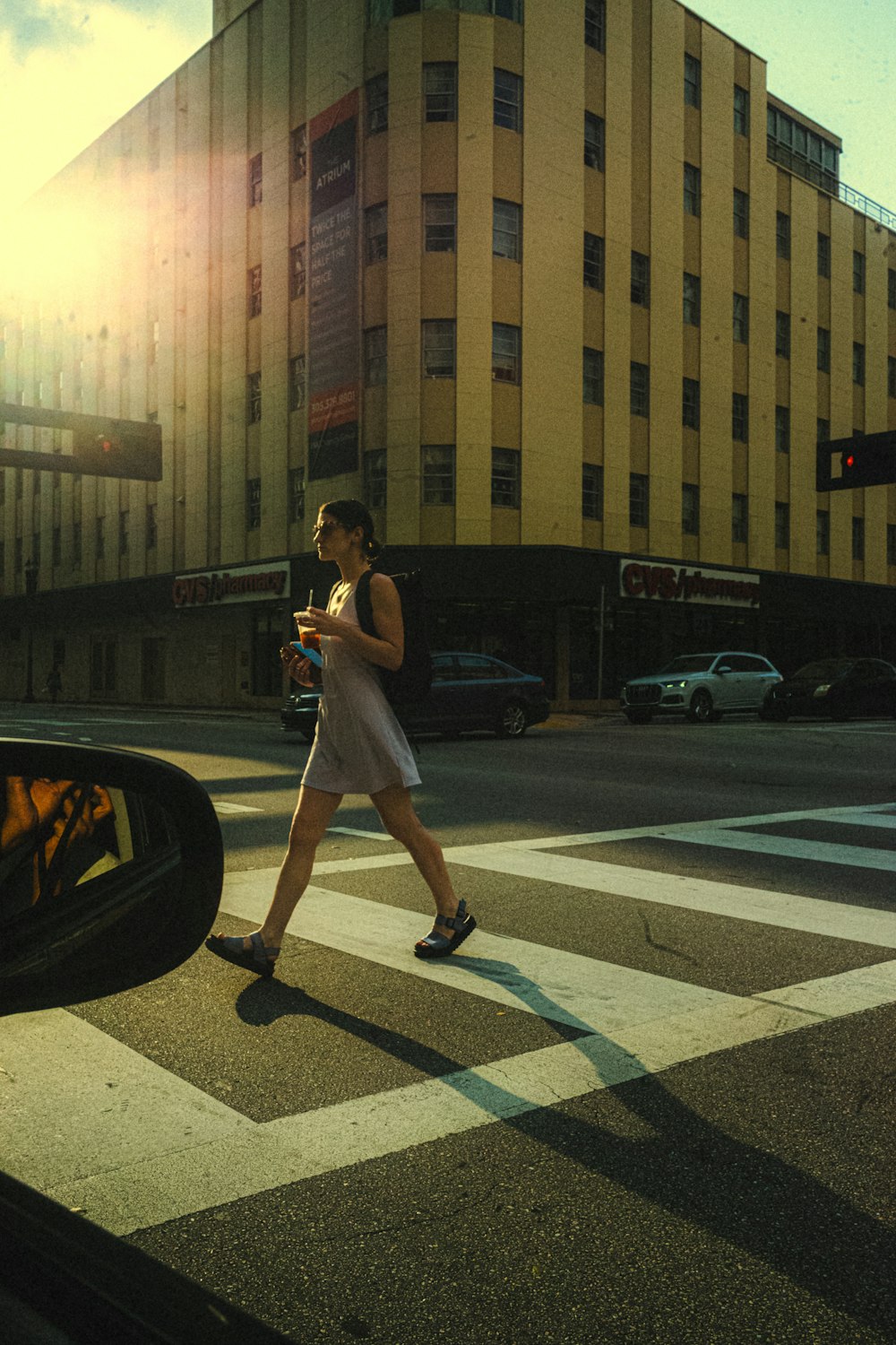 a woman walking across a street holding a cell phone