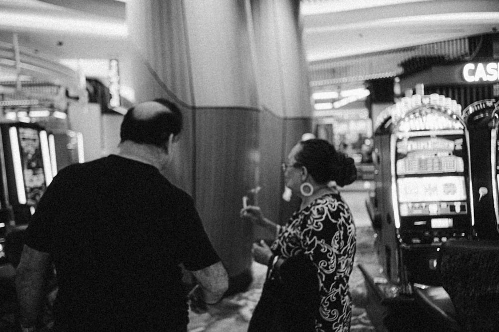 a man and a woman standing in front of slot machines