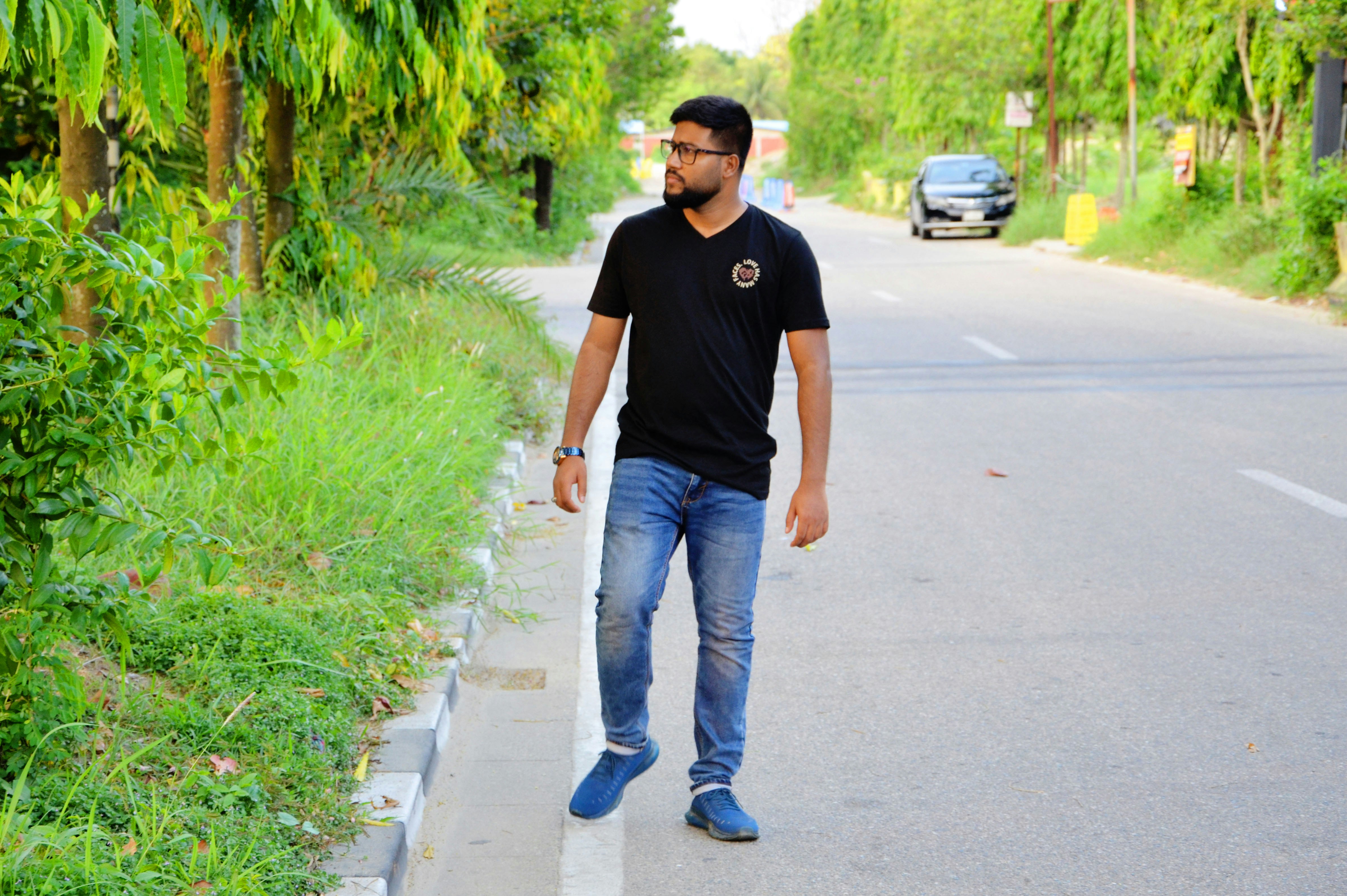 녹음이 우거진 숲 옆 거리를 걷고 있는 남자