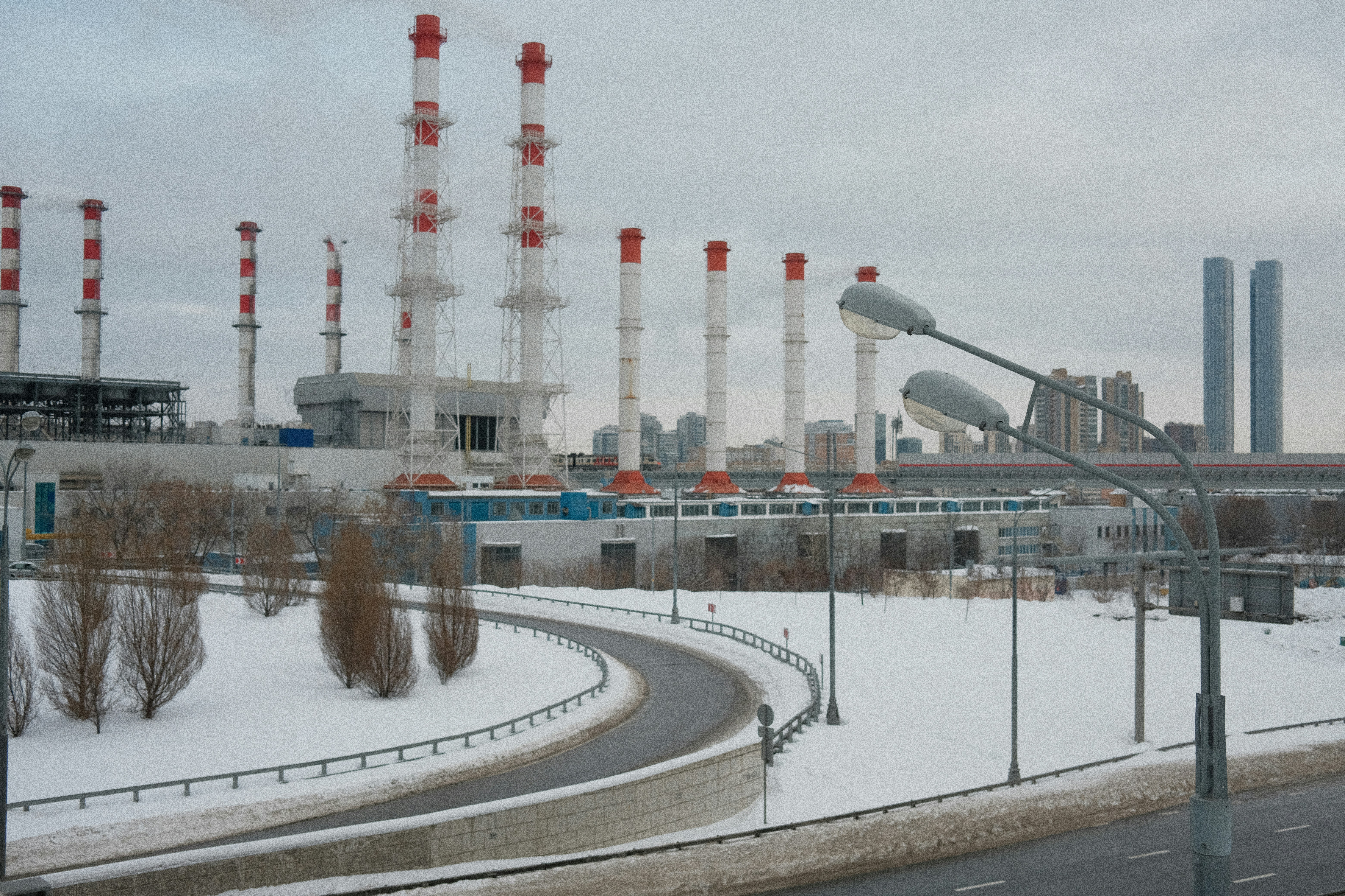 a snowy road with a factory in the background