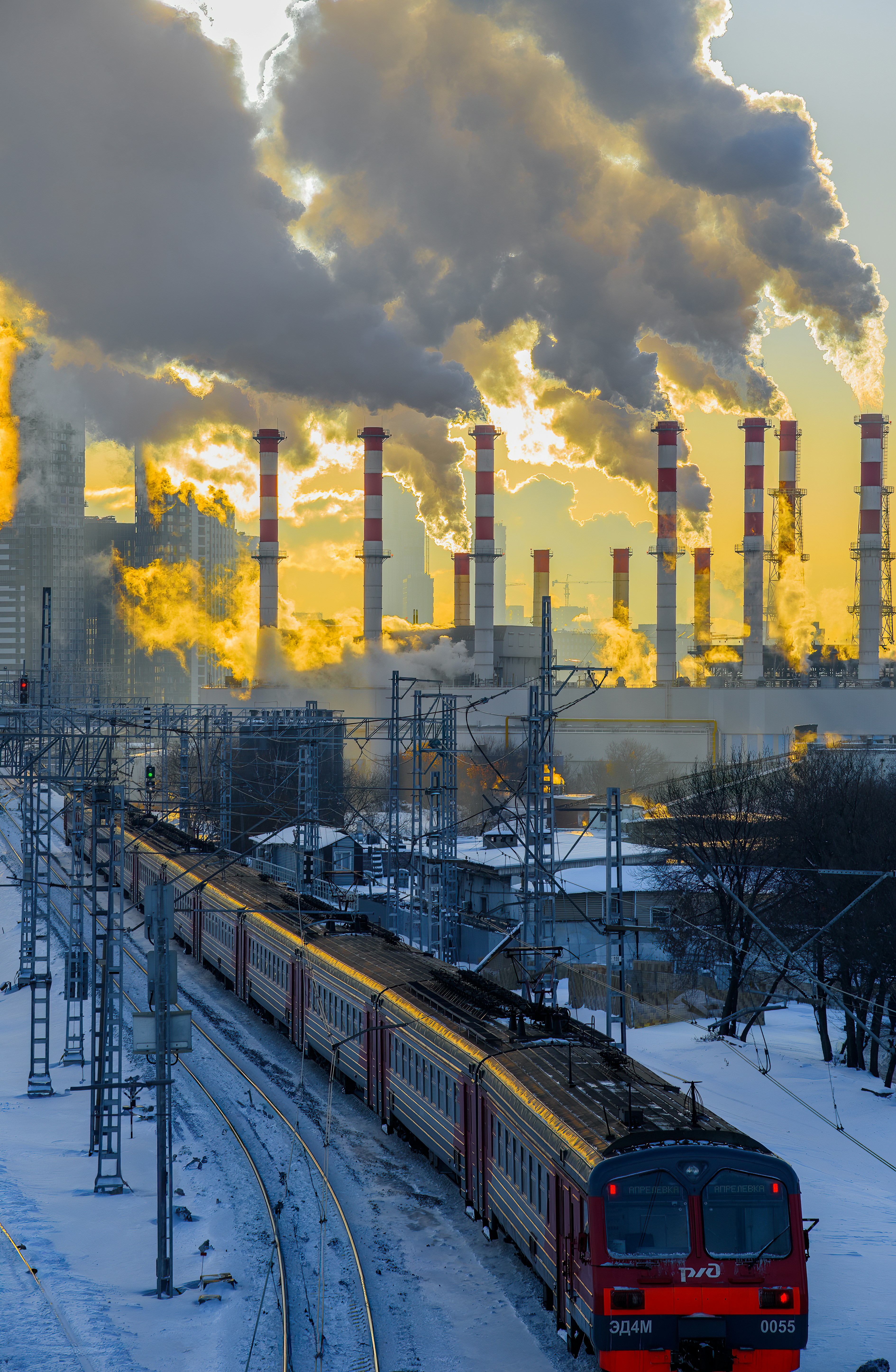a train traveling down tracks next to a factory