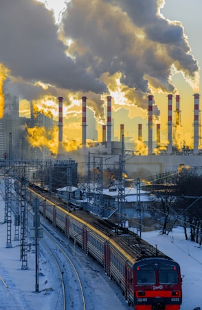 a train traveling down tracks next to a factory
