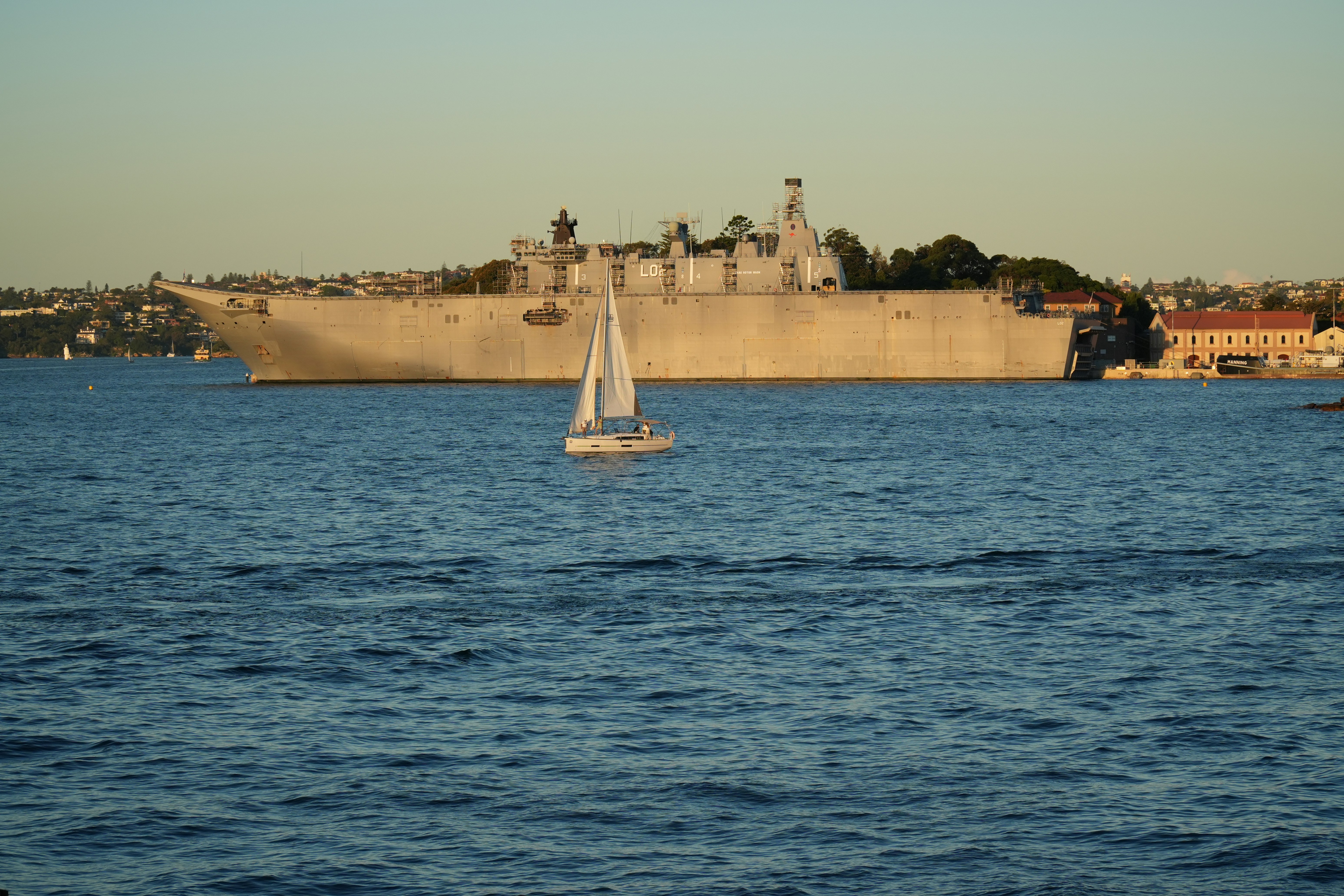 a sailboat in the water near a large ship