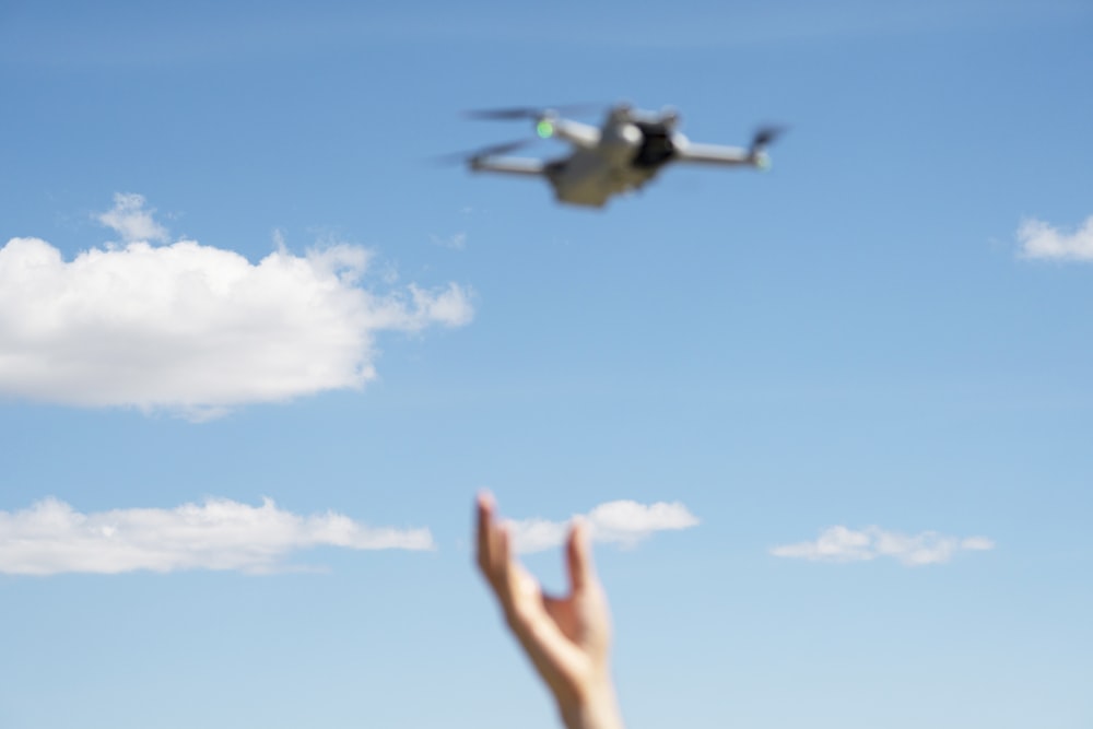 a person's hand reaching up towards a flying object