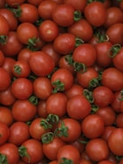 a pile of tomatoes with green leaves on them