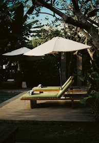 a lounge chair with an umbrella on a deck