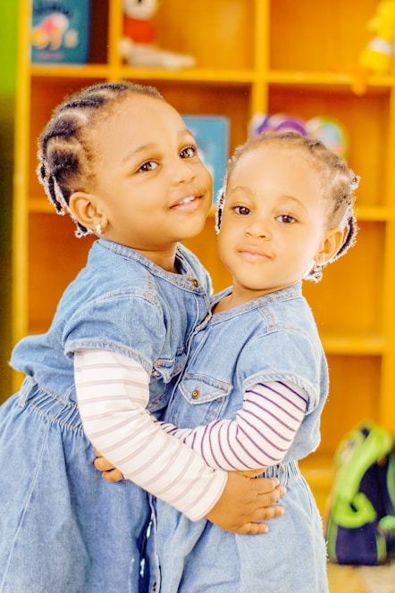 two young girls hugging each other in front of a bookshelf