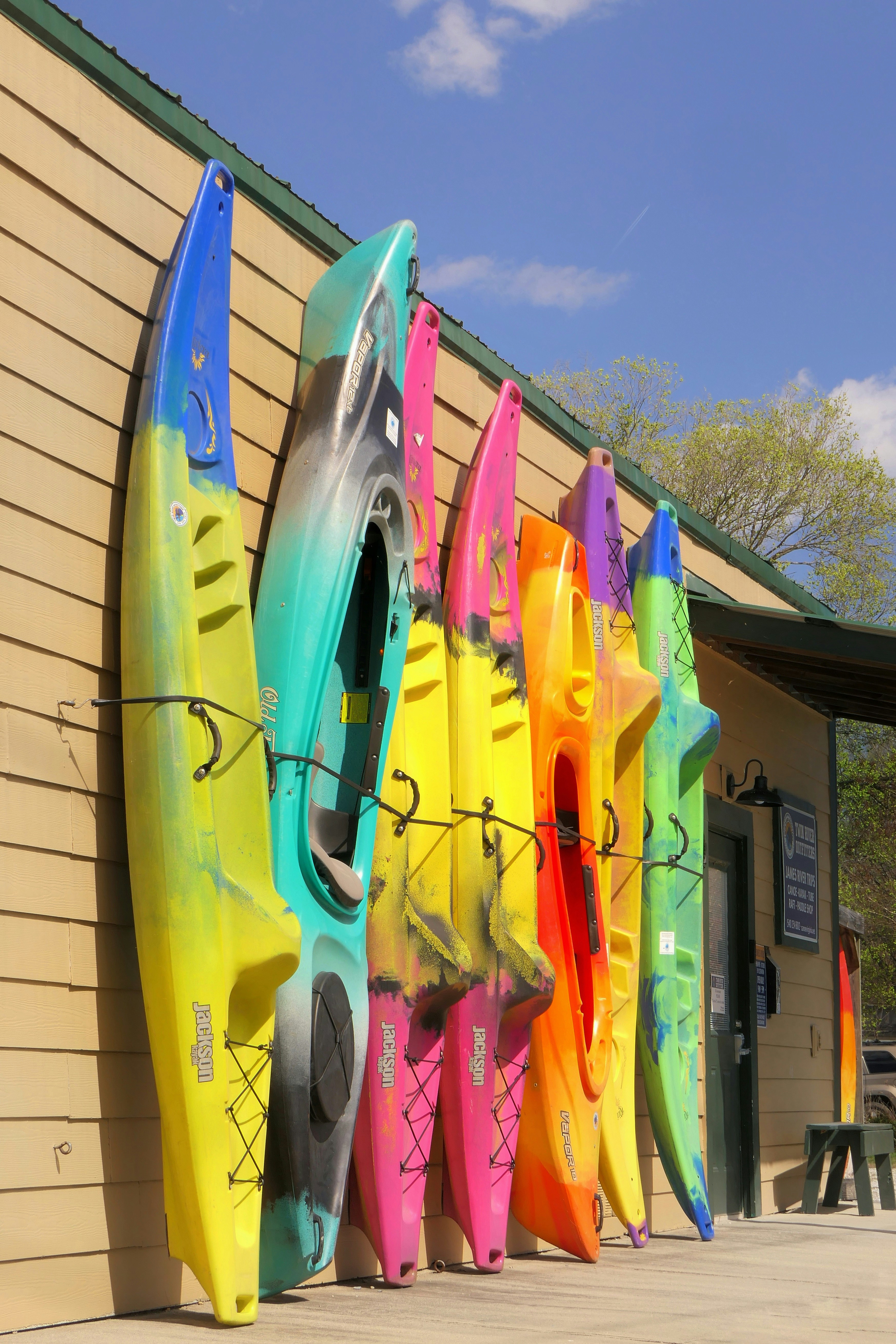 une rangée de kayaks colorés assis à côté d’un bâtiment