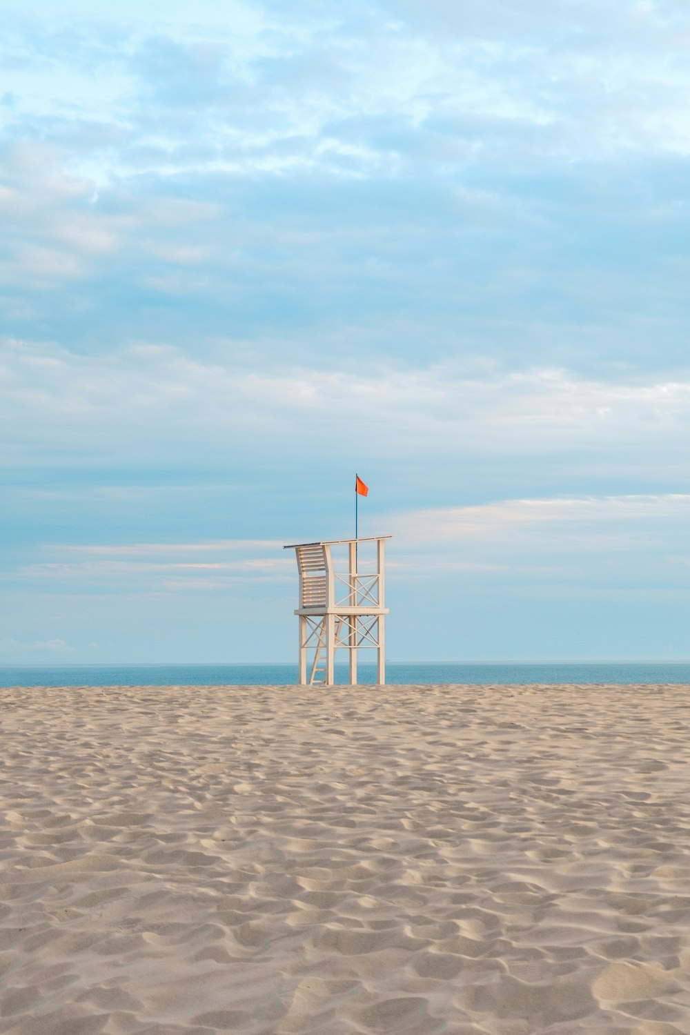 a white chair sitting on top of a sandy beach
