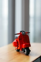 a red toy motorcycle sitting on top of a wooden table