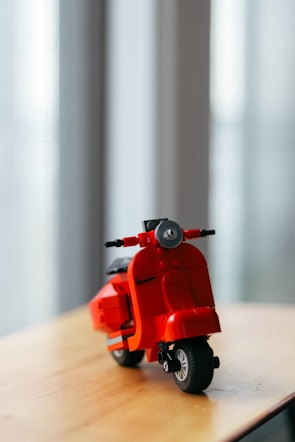 a red toy motorcycle sitting on top of a wooden table