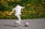 a young boy kicking a soccer ball on a road