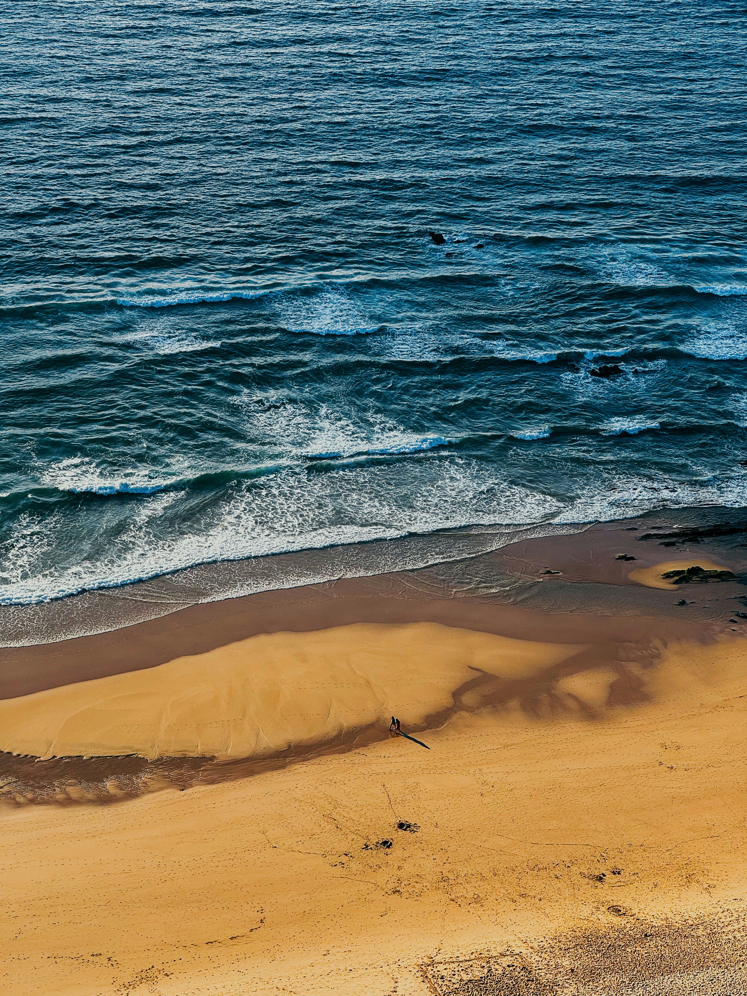 a sandy beach with waves coming in from the ocean