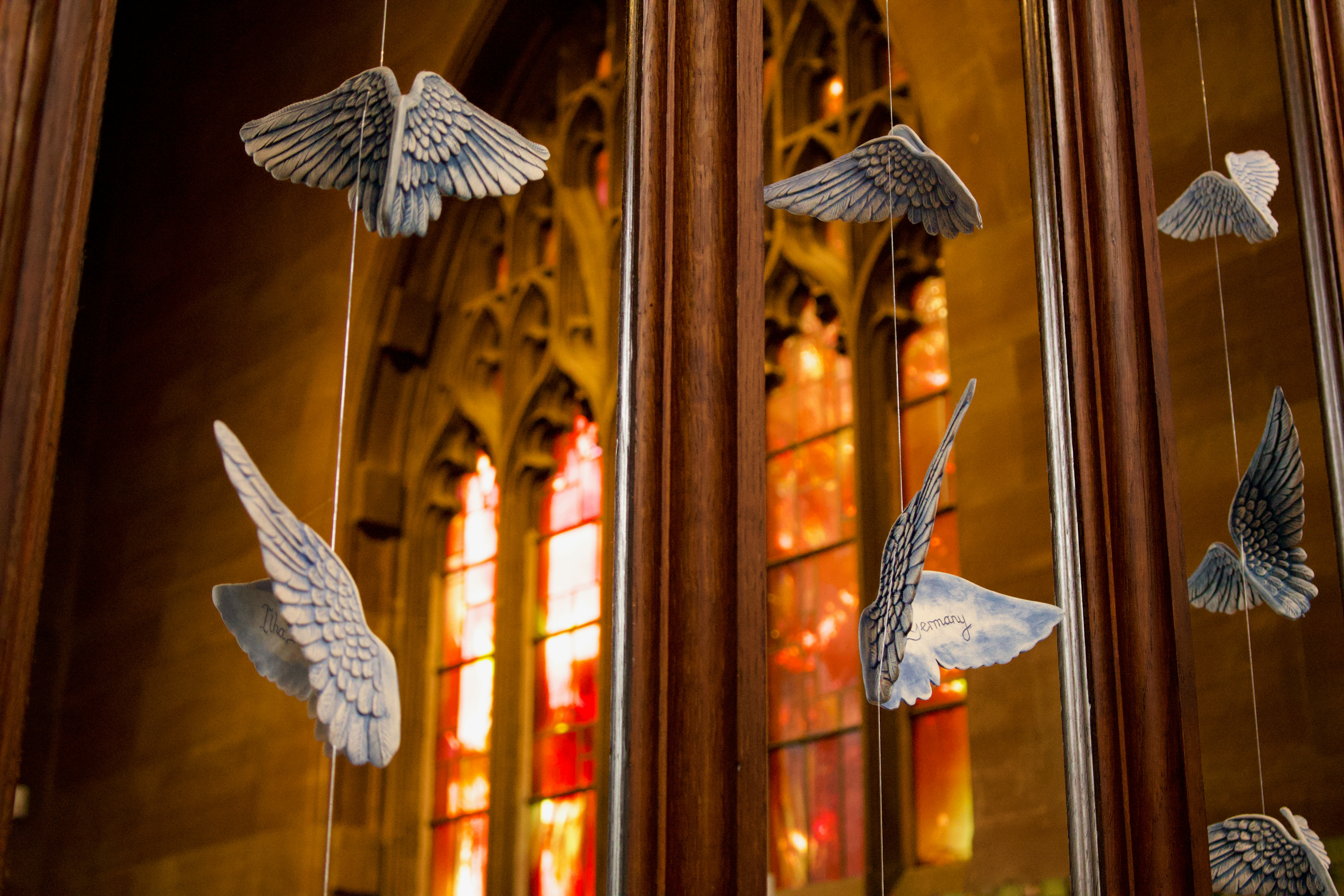 a group of paper birds hanging from strings in front of a stained glass window