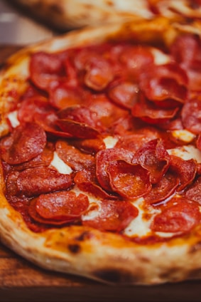 a pepperoni pizza sitting on top of a wooden cutting board
