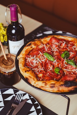 a pizza sitting on top of a pan next to a bottle of wine