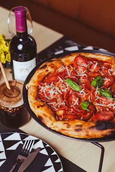 a pizza sitting on top of a pan next to a bottle of wine