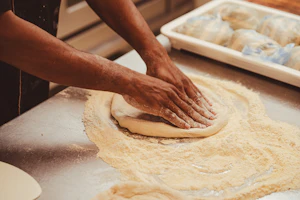 Massa de pizza sendo preparada à mão