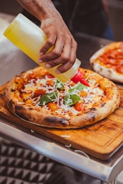 a person is putting cheese on a pizza