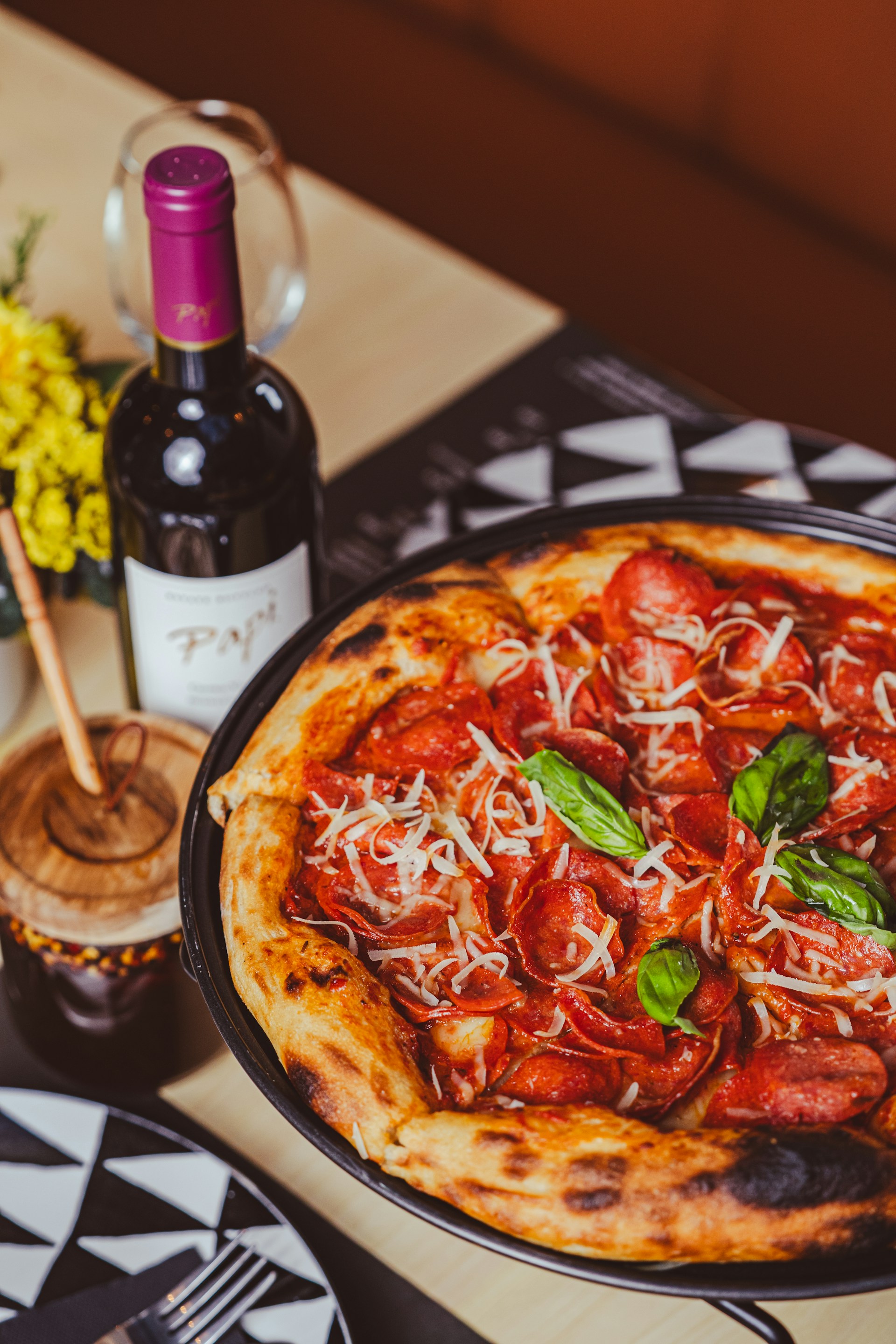 a pizza sitting on top of a pan next to a bottle of wine