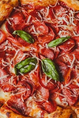 a close up of a pepperoni pizza with basil