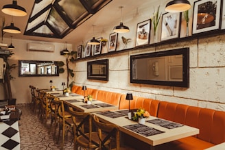 a restaurant with a long table and orange benches
