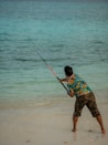 a young boy holding a fishing rod on the beach