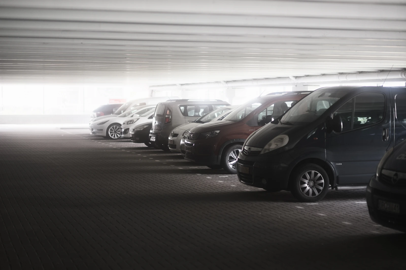 Fila de vehículos tipo van estacionados en un parqueadero cubierto
